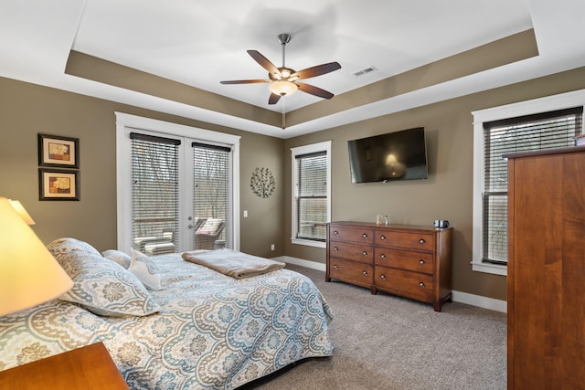 bedroom with ceiling fan, access to exterior, and a tray ceiling