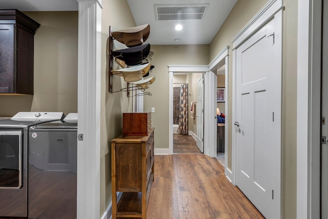 laundry area with cabinets, independent washer and dryer, and hardwood / wood-style flooring