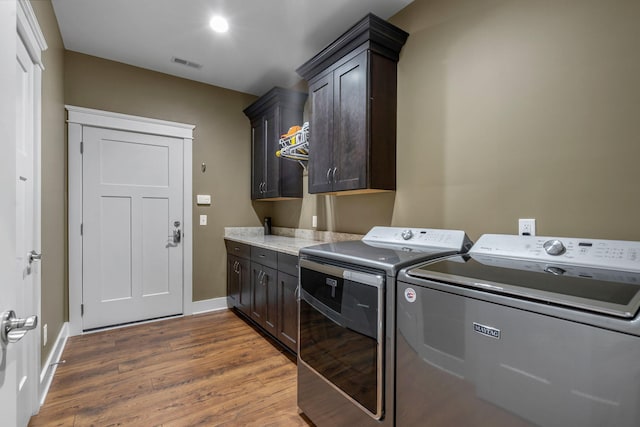 washroom with dark hardwood / wood-style floors, washing machine and clothes dryer, and cabinets