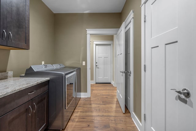 laundry area featuring washer and dryer, cabinets, and light hardwood / wood-style floors