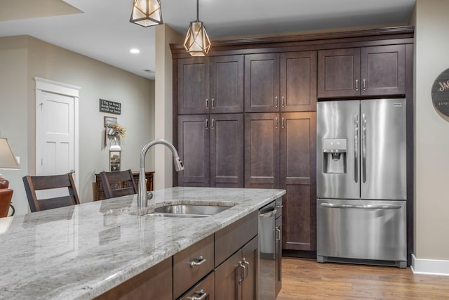 kitchen featuring a kitchen bar, appliances with stainless steel finishes, sink, and light stone counters