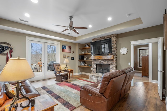 living room featuring french doors, a fireplace, ceiling fan, a raised ceiling, and hardwood / wood-style flooring