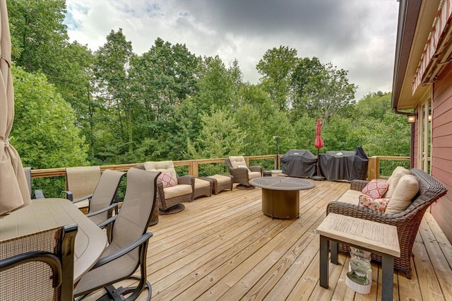 wooden deck with area for grilling and an outdoor living space with a fire pit