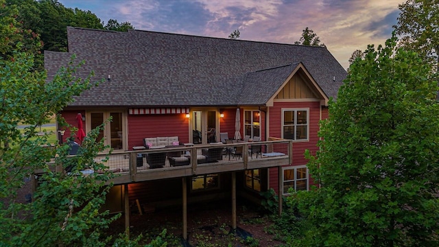 back house at dusk featuring a deck