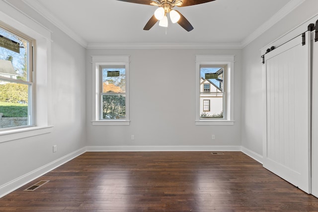 spare room featuring ceiling fan, a barn door, plenty of natural light, and ornamental molding