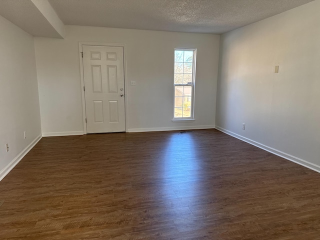 spare room featuring dark wood-type flooring and a textured ceiling