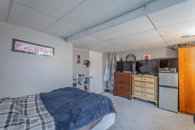 carpeted bedroom with a paneled ceiling and stainless steel refrigerator