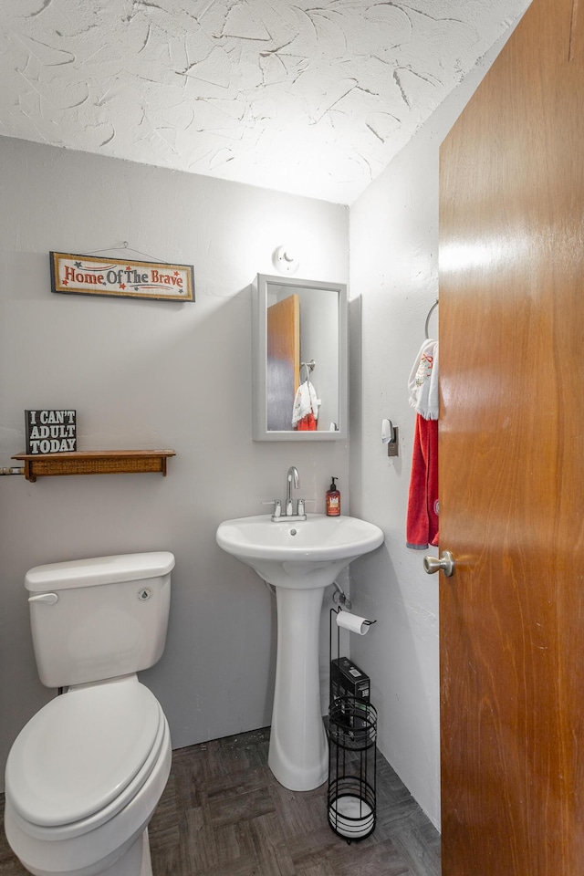 bathroom with parquet floors, sink, and toilet