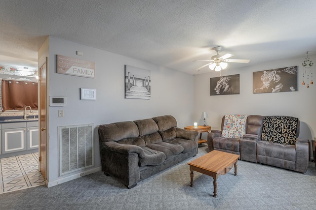 carpeted living room with ceiling fan, sink, and a textured ceiling