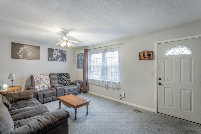 living room featuring ceiling fan, carpet floors, and a textured ceiling