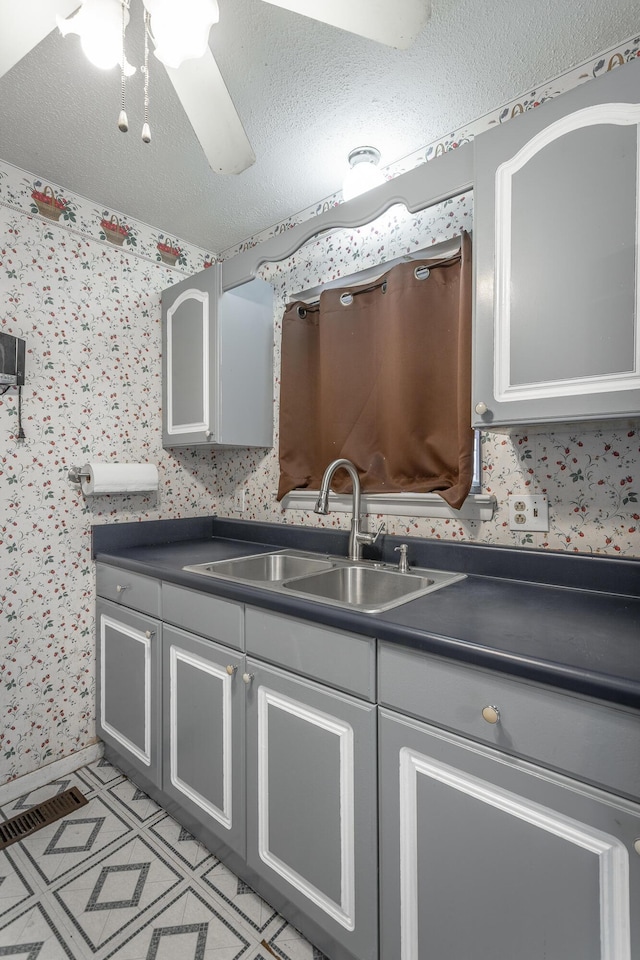 kitchen featuring sink, a textured ceiling, and gray cabinetry