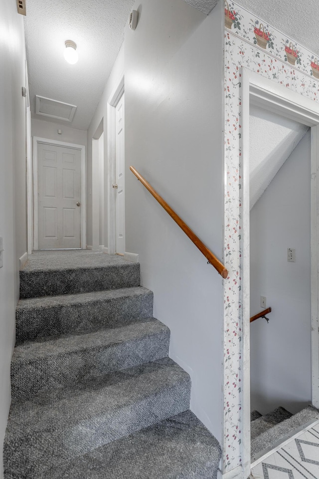 stairway featuring a textured ceiling