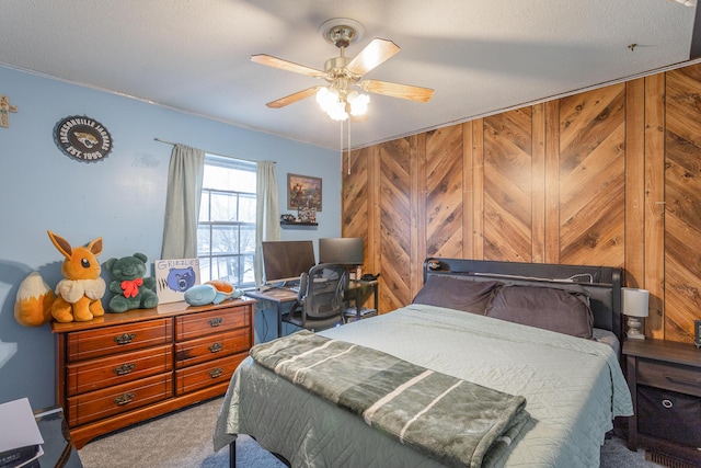 bedroom featuring ceiling fan, carpet flooring, a textured ceiling, and wood walls