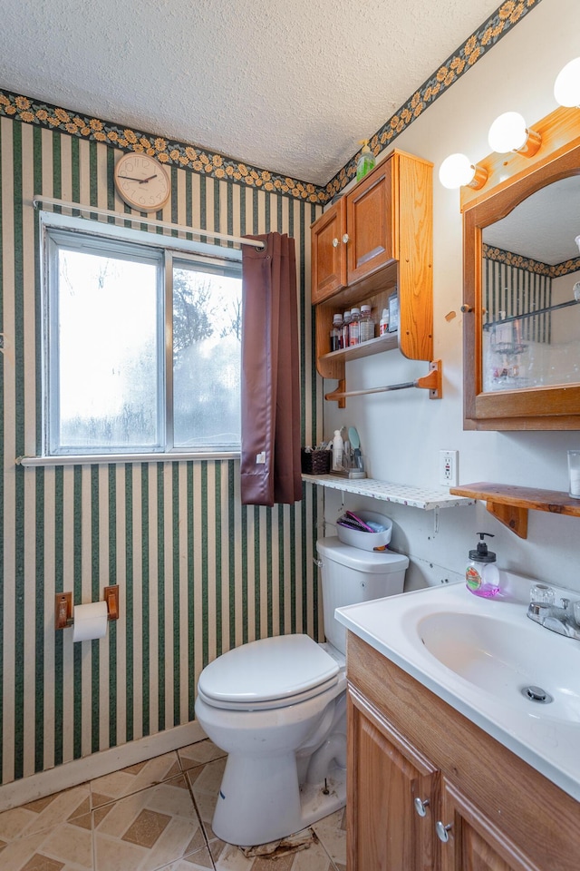 bathroom with vanity, toilet, and a textured ceiling