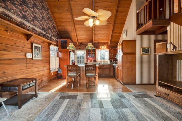 unfurnished dining area featuring sink, wood ceiling, high vaulted ceiling, wood walls, and beamed ceiling