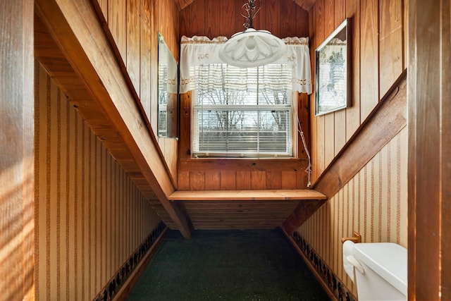 stairway featuring carpet flooring and wooden walls