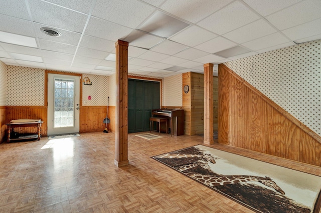 basement featuring wood walls, parquet floors, and a drop ceiling