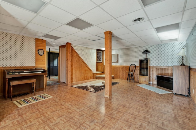 exercise area with wood walls, a paneled ceiling, and parquet flooring