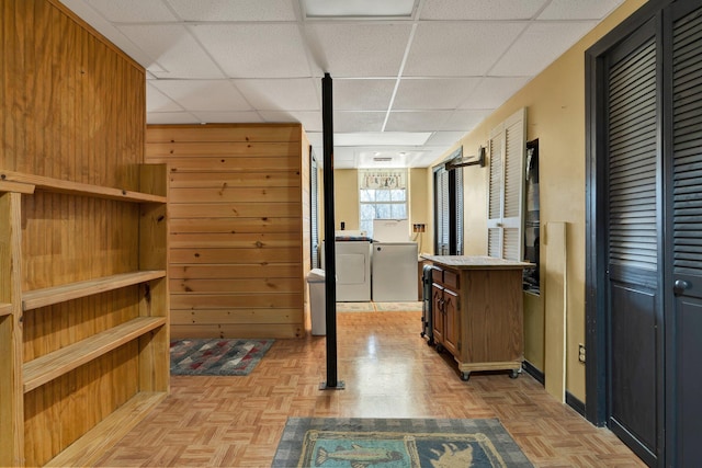 interior space featuring washing machine and dryer, wood walls, a paneled ceiling, and light parquet flooring