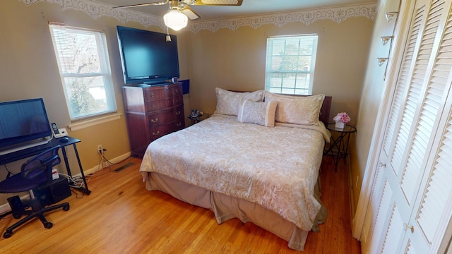 bedroom featuring ceiling fan, multiple windows, and hardwood / wood-style floors