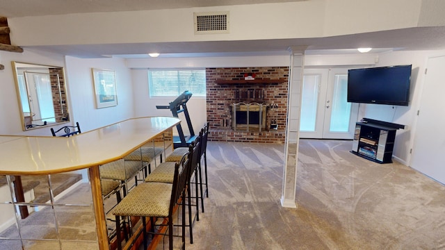 carpeted dining area with french doors and a brick fireplace