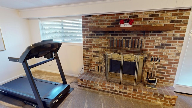 exercise room with a brick fireplace, carpet, ornamental molding, and a healthy amount of sunlight