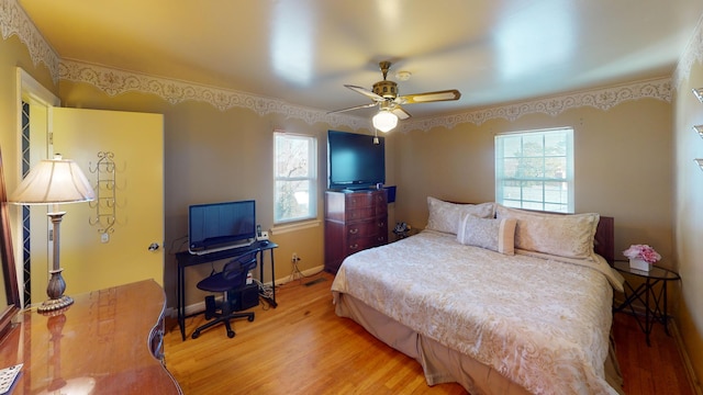 bedroom with ceiling fan, multiple windows, and light hardwood / wood-style flooring