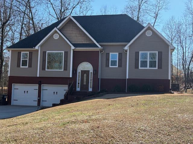 raised ranch featuring a garage and a front yard