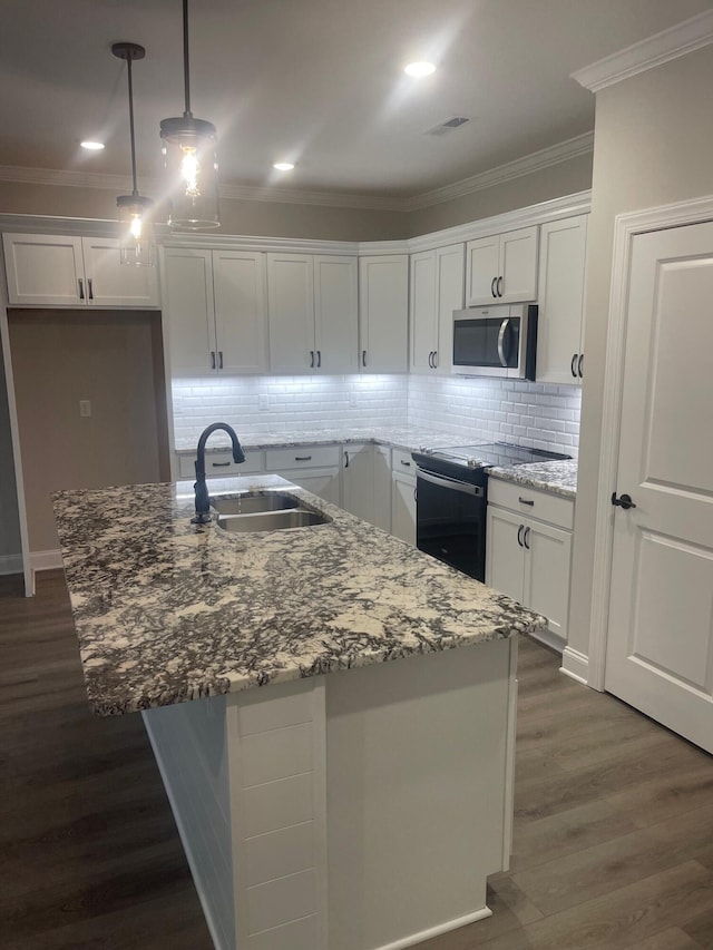 kitchen featuring backsplash, black range with electric stovetop, sink, a kitchen island with sink, and white cabinets