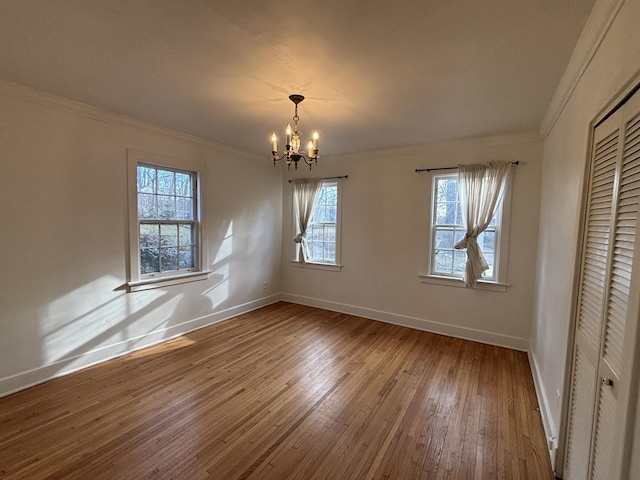 unfurnished dining area with hardwood / wood-style floors, crown molding, and a chandelier