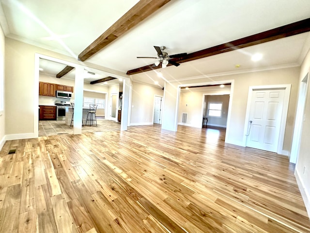 unfurnished living room featuring ceiling fan, a wealth of natural light, ornamental molding, and light hardwood / wood-style flooring