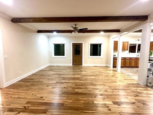 unfurnished living room with ceiling fan, light wood-type flooring, beamed ceiling, and ornamental molding