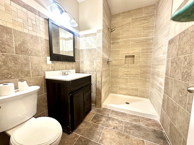 bathroom featuring tile walls, tiled shower, vanity, and toilet