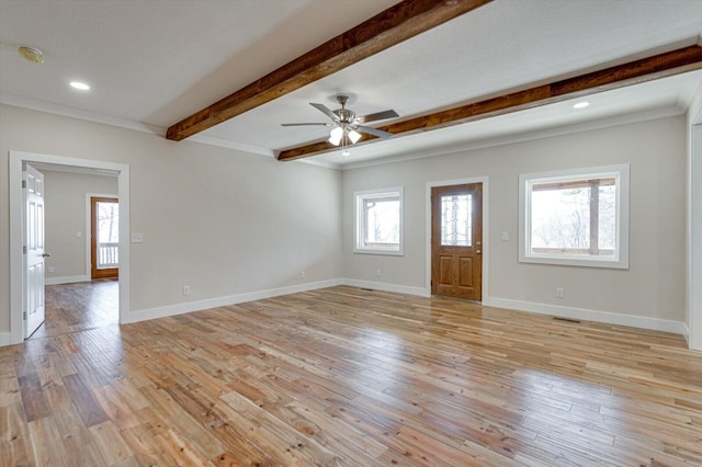 unfurnished room with beamed ceiling, a wealth of natural light, and light hardwood / wood-style flooring