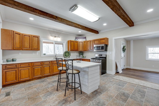 kitchen featuring sink, a breakfast bar area, a kitchen island, stainless steel appliances, and beam ceiling