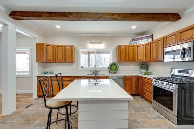 kitchen with beam ceiling, appliances with stainless steel finishes, a center island, and a breakfast bar