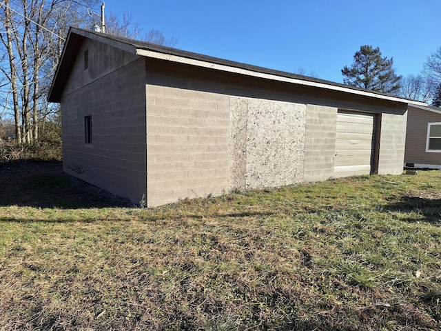 view of side of home featuring a garage, an outdoor structure, and a lawn