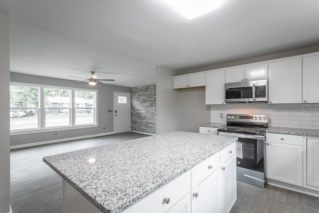 kitchen with white cabinetry, dark hardwood / wood-style flooring, a kitchen island, stainless steel appliances, and backsplash