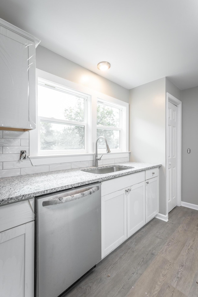 kitchen with white cabinetry, dishwasher, sink, light hardwood / wood-style floors, and light stone countertops