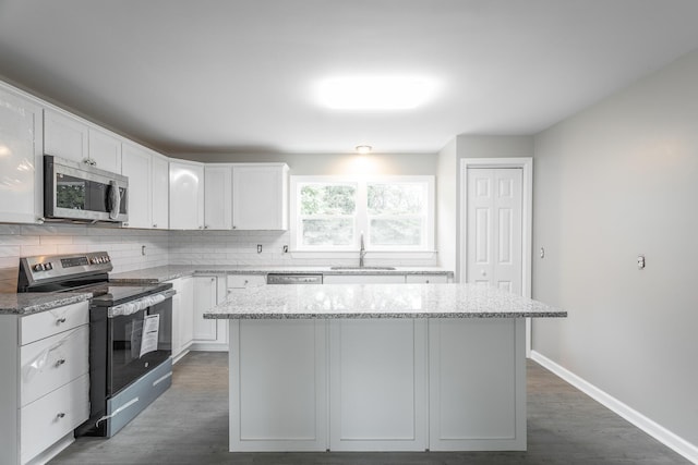 kitchen featuring sink, white cabinets, a center island, light stone counters, and stainless steel appliances