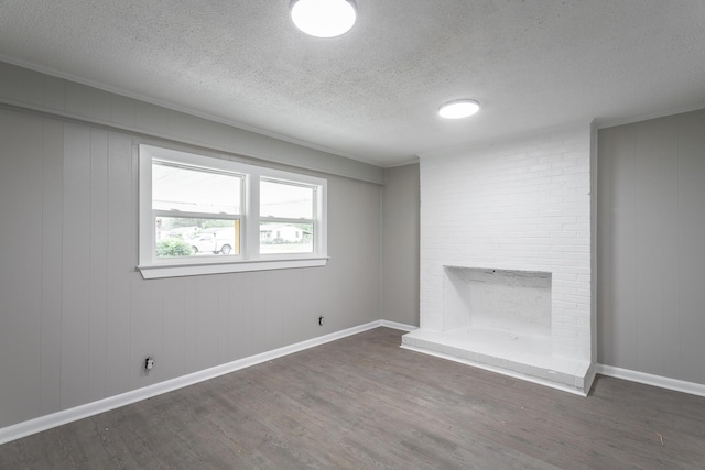 unfurnished room featuring ornamental molding, dark hardwood / wood-style flooring, a brick fireplace, and a textured ceiling