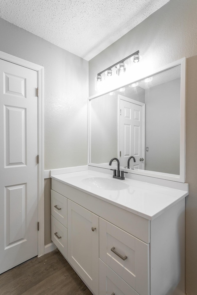 bathroom with hardwood / wood-style flooring, vanity, and a textured ceiling