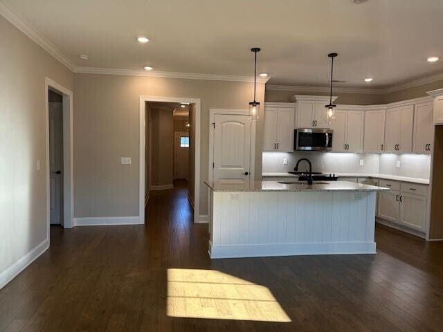 kitchen with sink, an island with sink, white cabinets, and decorative light fixtures