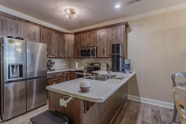 kitchen featuring light wood-type flooring, kitchen peninsula, appliances with stainless steel finishes, and sink