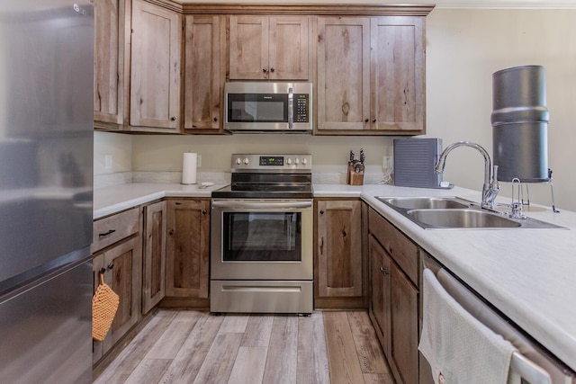 kitchen featuring stainless steel appliances, light hardwood / wood-style floors, and sink