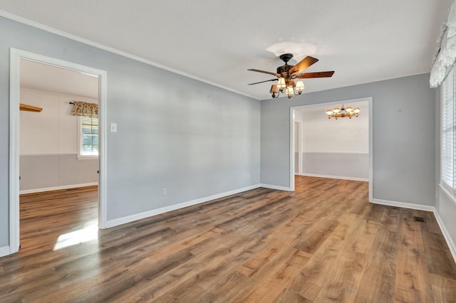 unfurnished room featuring ceiling fan with notable chandelier, hardwood / wood-style floors, and ornamental molding