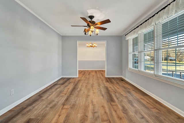 empty room featuring ornamental molding, ceiling fan with notable chandelier, and hardwood / wood-style floors