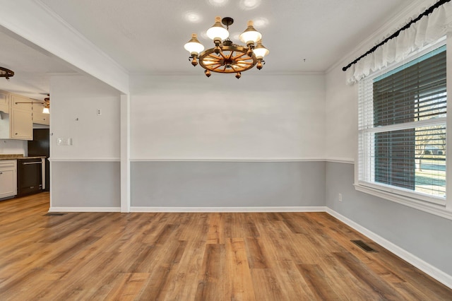 spare room with ceiling fan with notable chandelier, crown molding, and light wood-type flooring