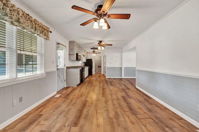 interior space featuring black appliances, white cabinets, ornamental molding, and light hardwood / wood-style floors