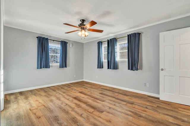 empty room with a wealth of natural light, crown molding, and hardwood / wood-style floors